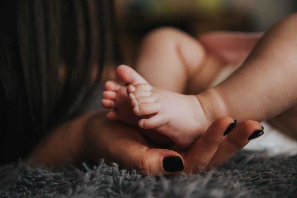 licença maternidade no eSocial: na foto, uma mão feminina adulta segurando os pés de um bebê.